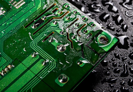 green printed circuit board (PCB) with visible water droplets on its surface