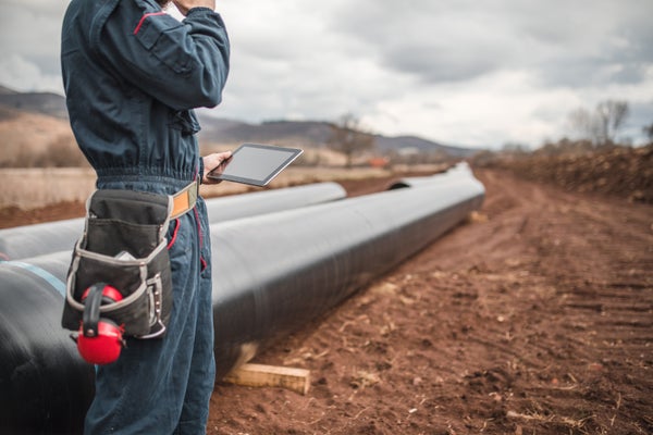 Worker evaluating above ground pipeline for Tapecoat application